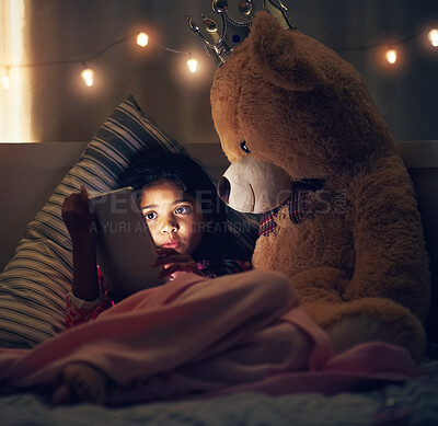 Buy stock photo Night, teddy bear and girl with tablet, kid and relaxing with screen light, online reading and social media. Bedroom, home and child with tech, stuffed animal and dark with internet and digital app