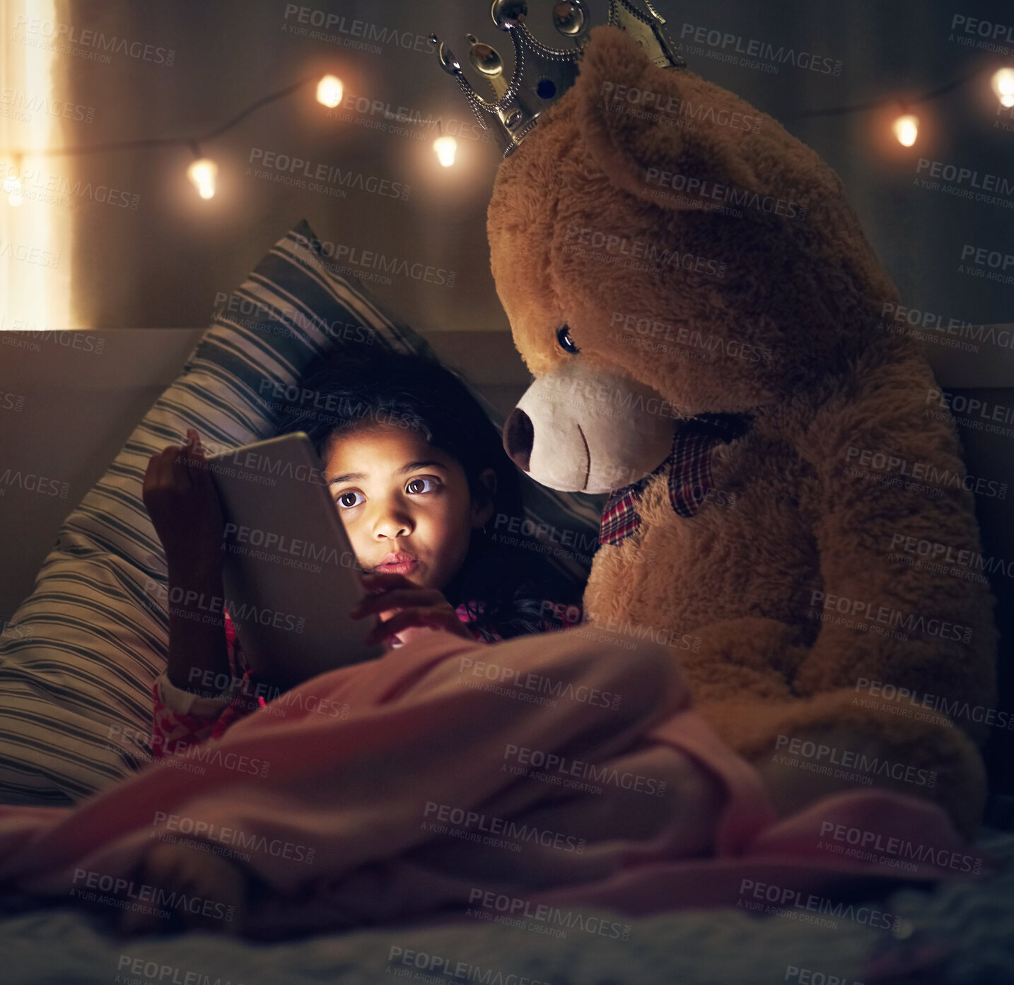 Buy stock photo Night, teddy bear and girl with tablet, kid and relaxing with screen light, online reading and social media. Bedroom, home and child with tech, stuffed animal and dark with internet and digital app