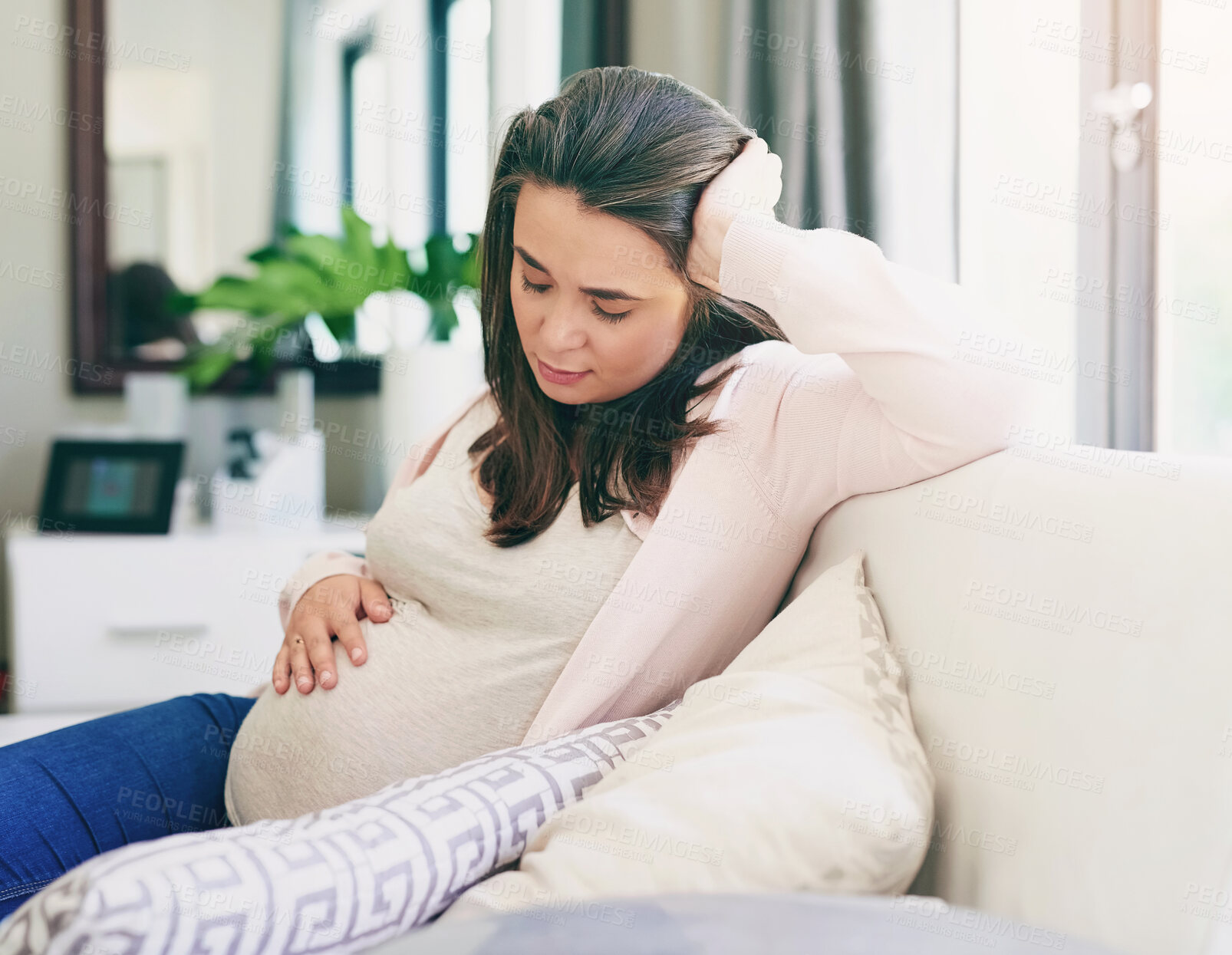 Buy stock photo Health, pregnancy and woman with hand on stomach  for comfort and support on sofa at home. Healthcare, female person or mother and wellness with worry and stress for belly in maternity on couch