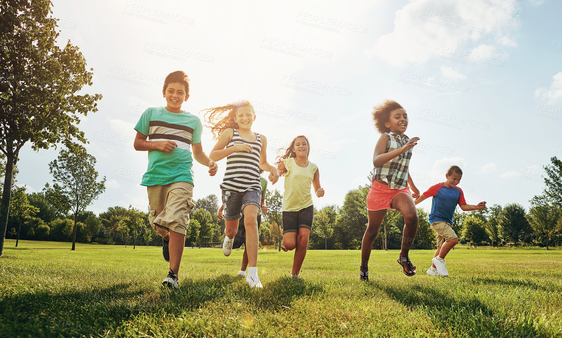 Buy stock photo Happy friends, children and running with grass field in nature for fun, playful day or sunshine at park. Diversity or group of excited kids or youth enjoying sunny outdoor holiday or weekend together