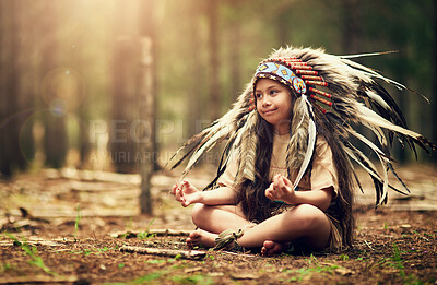 Buy stock photo Nature, forest and child in Native American costume for meditation, tradition and culture. Trees, relax and kid on floor in woods with feather head gear, indigenous cosplay and outdoor childhood fun.