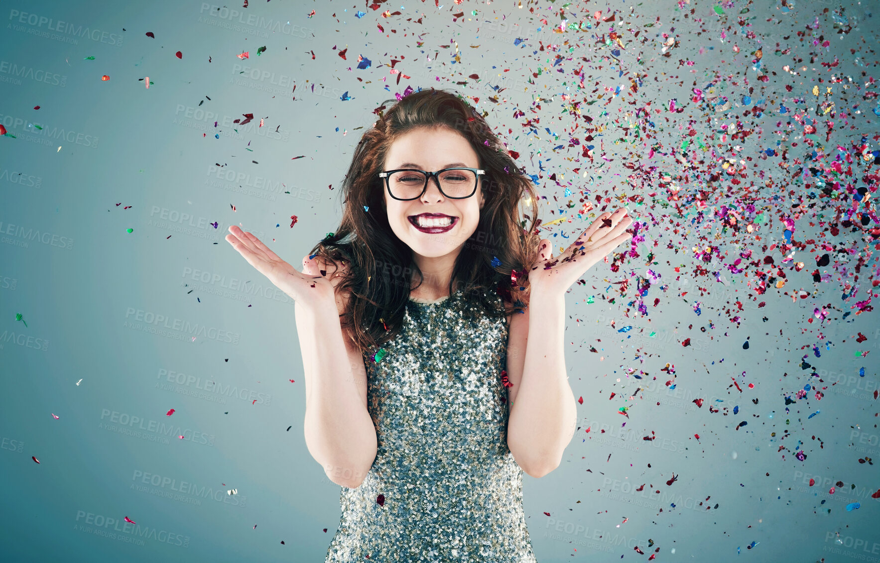 Buy stock photo Happy, celebration and woman on blue background with confetti for success, winning and birthday surprise. Winner, excited and isolated person with glitter for party, prize and achievement in studio