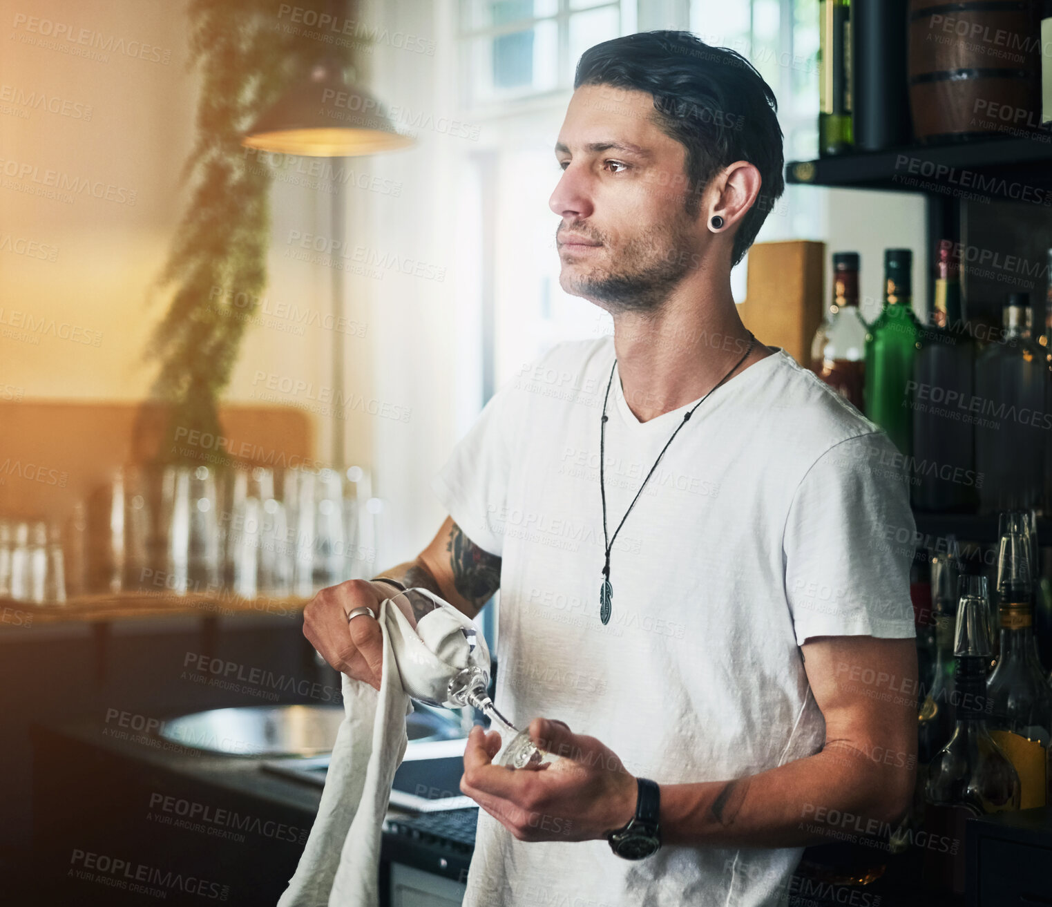 Buy stock photo Waiter, man and cleaning a glass in pub with thinking, daydreaming and wondering with hygiene and maintenance. Bartender, person and thoughtful in restaurant with polishing, disinfection and bacteria
