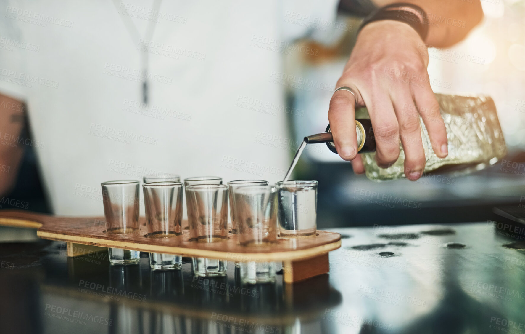 Buy stock photo Hands, shot glasses and bartender pouring for order, service and alcohol at social lounge in nightclub. Person, barman and bottle of liquor, spirits and discount for drinks at happy hour event in pub