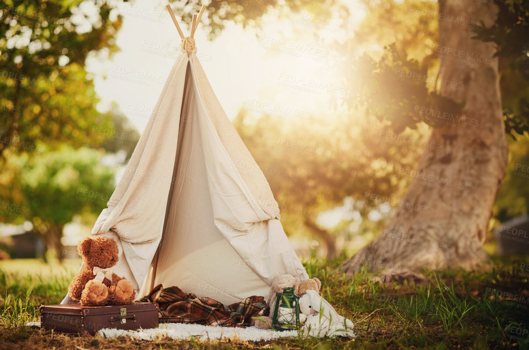 Buy stock photo Teepee, tent and fun in garden outdoor in nature for children, playing and camp for adventure or imagination. Cloth, shelter and fantasy house for kids in forest with blanket, suitcase and teddy bear