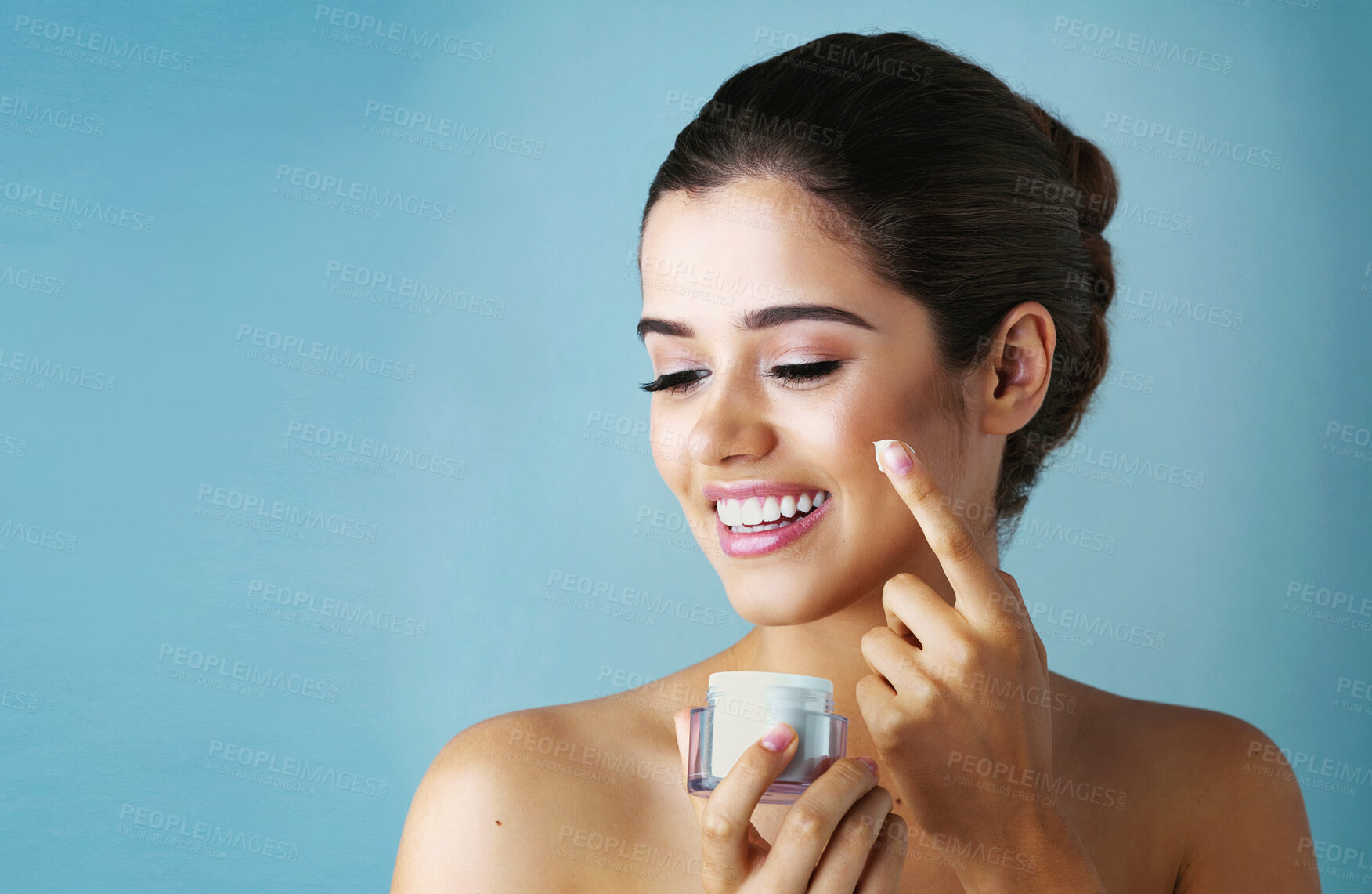 Buy stock photo Happy woman, lotion and skincare with container for facial treatment on a blue studio background. Female person or young model with smile for cosmetics or anti aging cream in dermatology on mockup