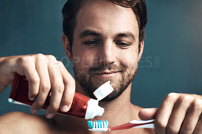 Buy stock photo Face, toothbrush and toothpaste with man in studio isolated on blue background for dental care. Brushing teeth, oral hygiene and product with person in bathroom, cleaning mouth for protection