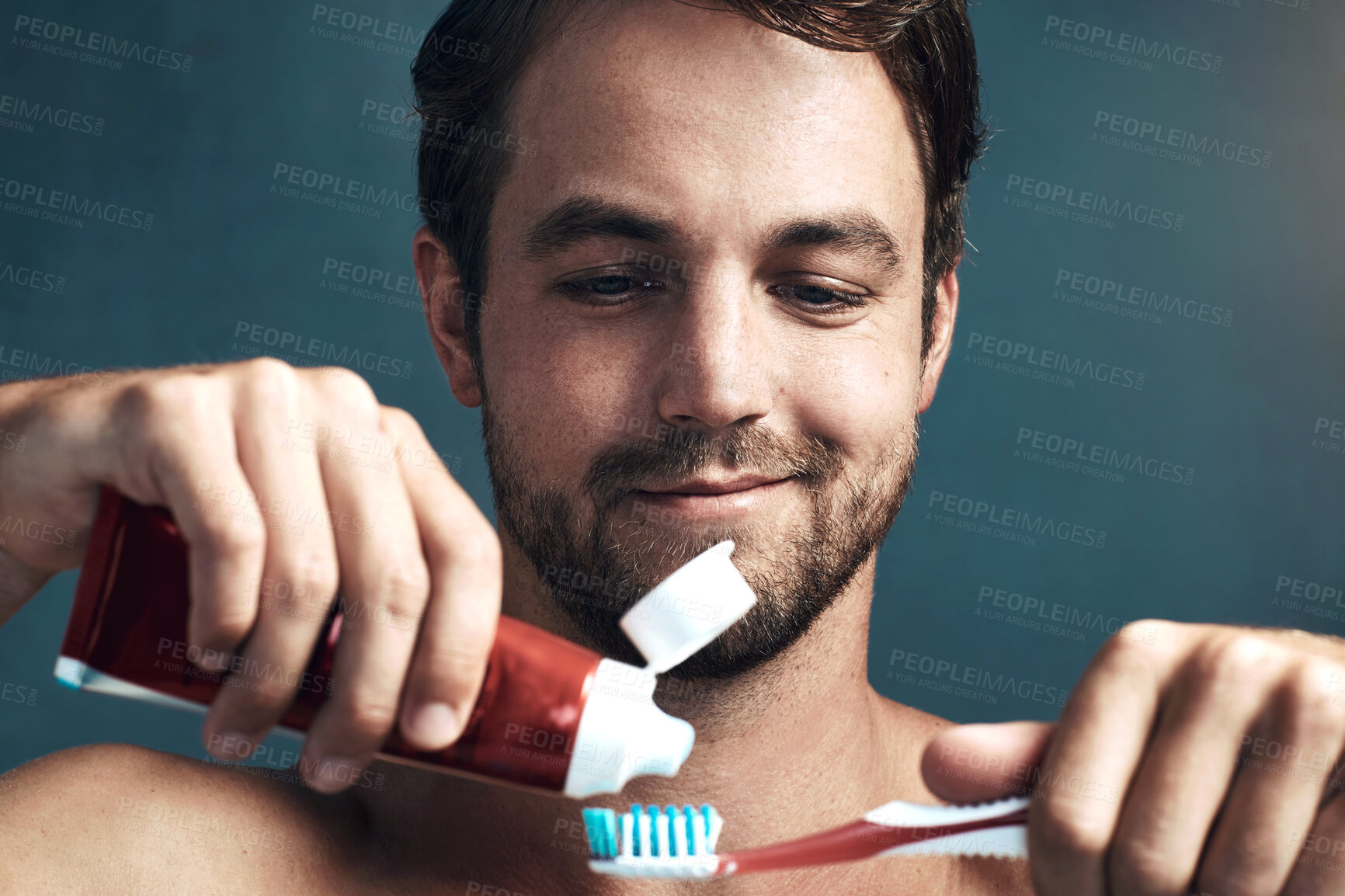 Buy stock photo Face, toothbrush and toothpaste with man in studio isolated on blue background for dental care. Brushing teeth, oral hygiene and product with person in bathroom, cleaning mouth for protection