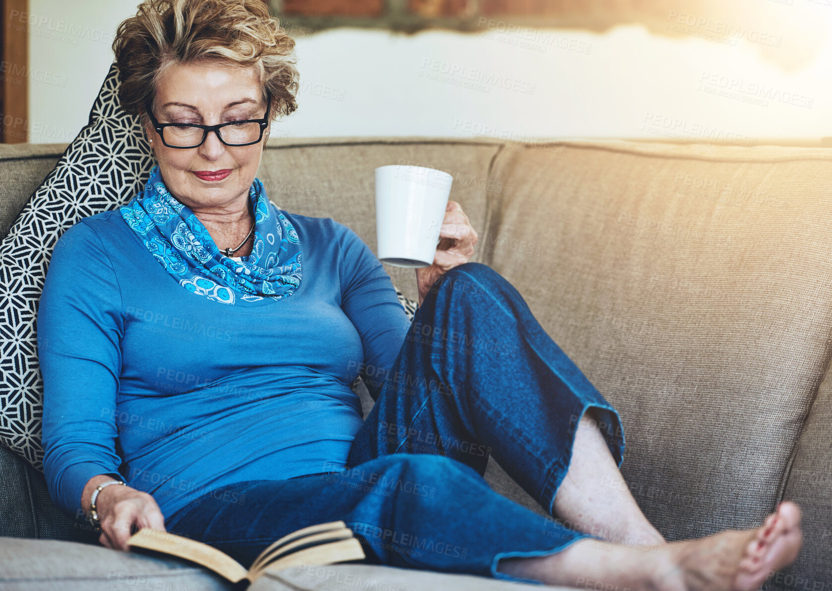 Buy stock photo Senior woman, book and coffee with living room, sofa and relaxing for retirement rest. Lady, cup and warm beverage with novel, reading and house for entertainment, study or knowledge with story