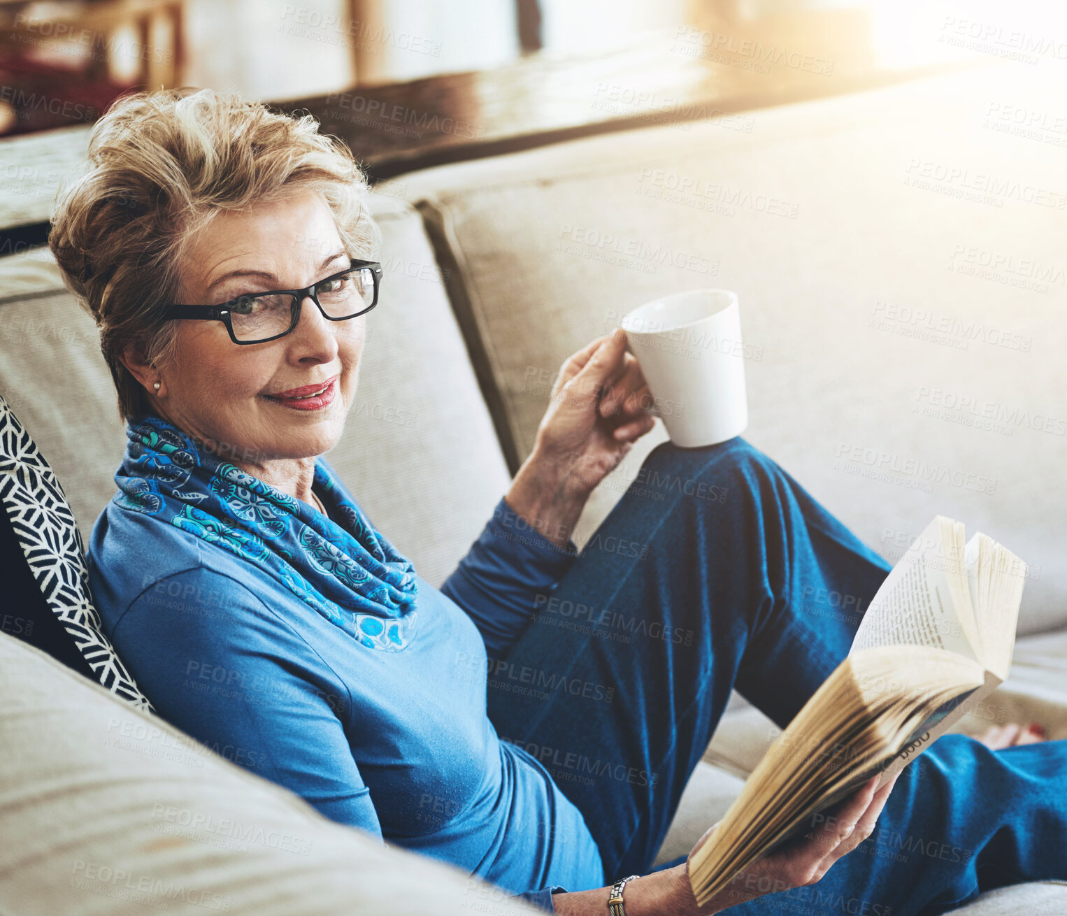 Buy stock photo Happy, senior woman and glasses with book or story on sofa funny literature in retirement home. Grandma, novel and drink on couch for rest, relax and comfort with reading hobby for entertainment