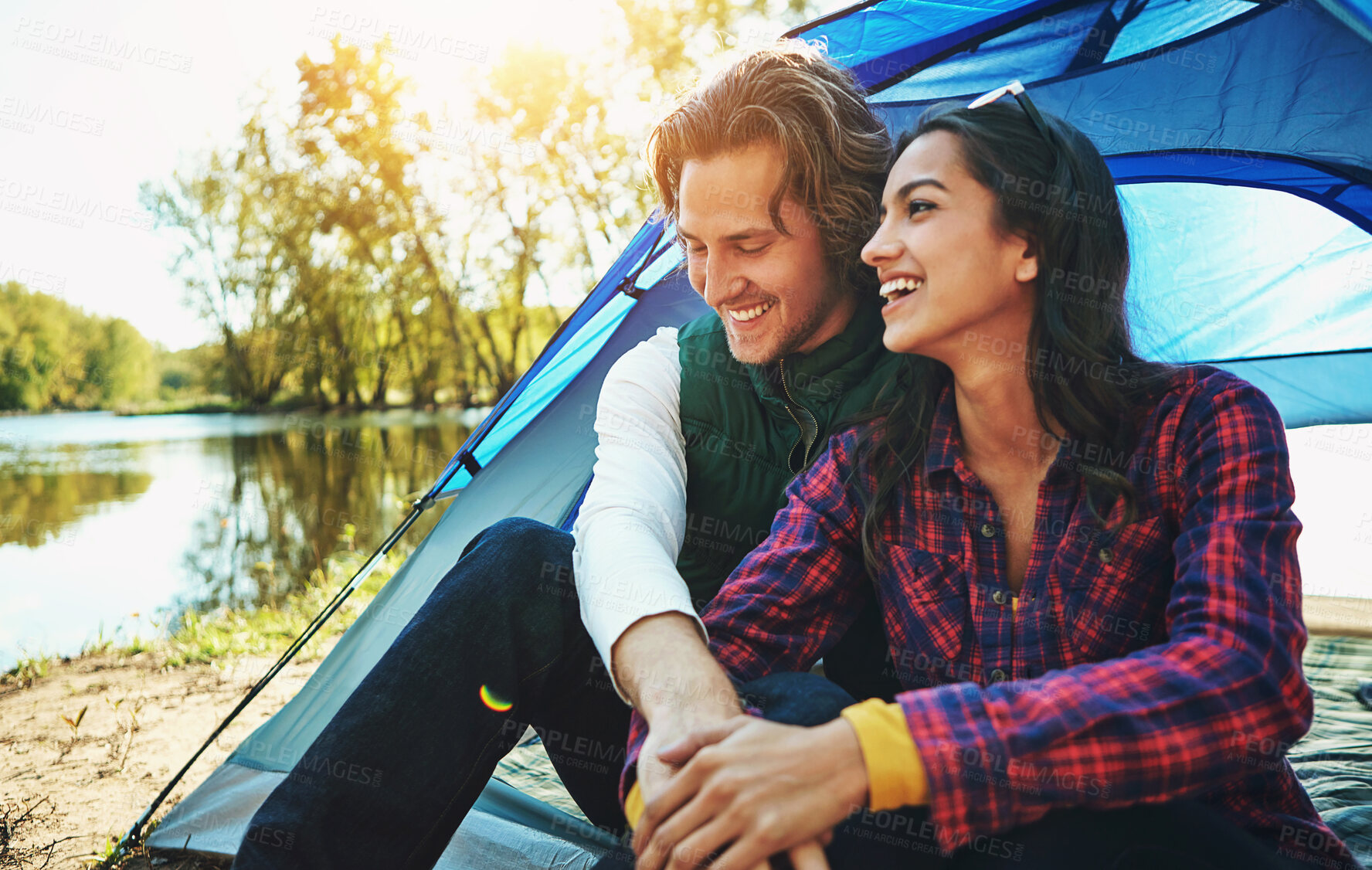 Buy stock photo Camping, holiday and couple in tent with love and happiness together on adventure in woods at lake. People, embrace or relax outdoor in nature with funny chat on vacation or travel to river in forest