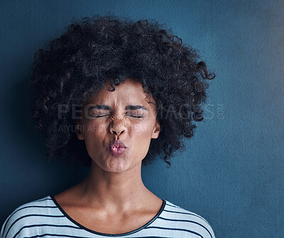 Buy stock photo Black woman, emoji and kissing with funny face in studio for fun, relax and playful attitude on blue background. Lady, comic and goofy portrait with facial expression, crazy and personality isolated