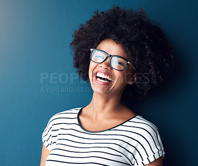 Buy stock photo Portrait, funny and woman with glasses, smile and confident girl on blue studio background. Face, person and model with eyewear, afro and laughing for joke, humor and happiness with joy and cheerful