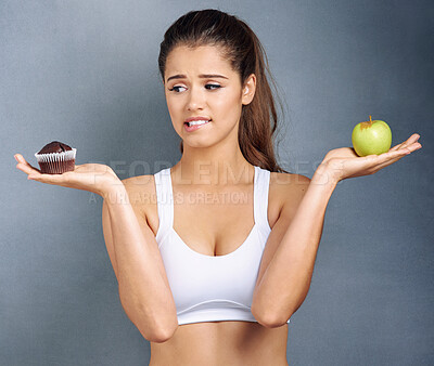 Buy stock photo Woman, food and thinking of choice in studio with apple, muffin and confused with diet decision for healthy body. Girl, athlete and meal option with fruit, cake and contemplation on gray background