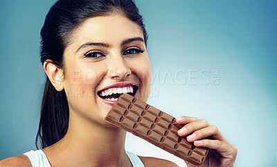 Buy stock photo Woman, portrait and happy snack and chocolate for treat and delicious, isolated on blue background. Smile, face and candy, eating with female model in studio and tasting food, dessert or sweets