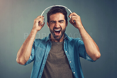 Buy stock photo Excited, man and headphones for music in studio backdrop for edgy, cheerful on gray background. Male person, expression and tech for streaming, sound or audio for energy or confidence in denim shirt