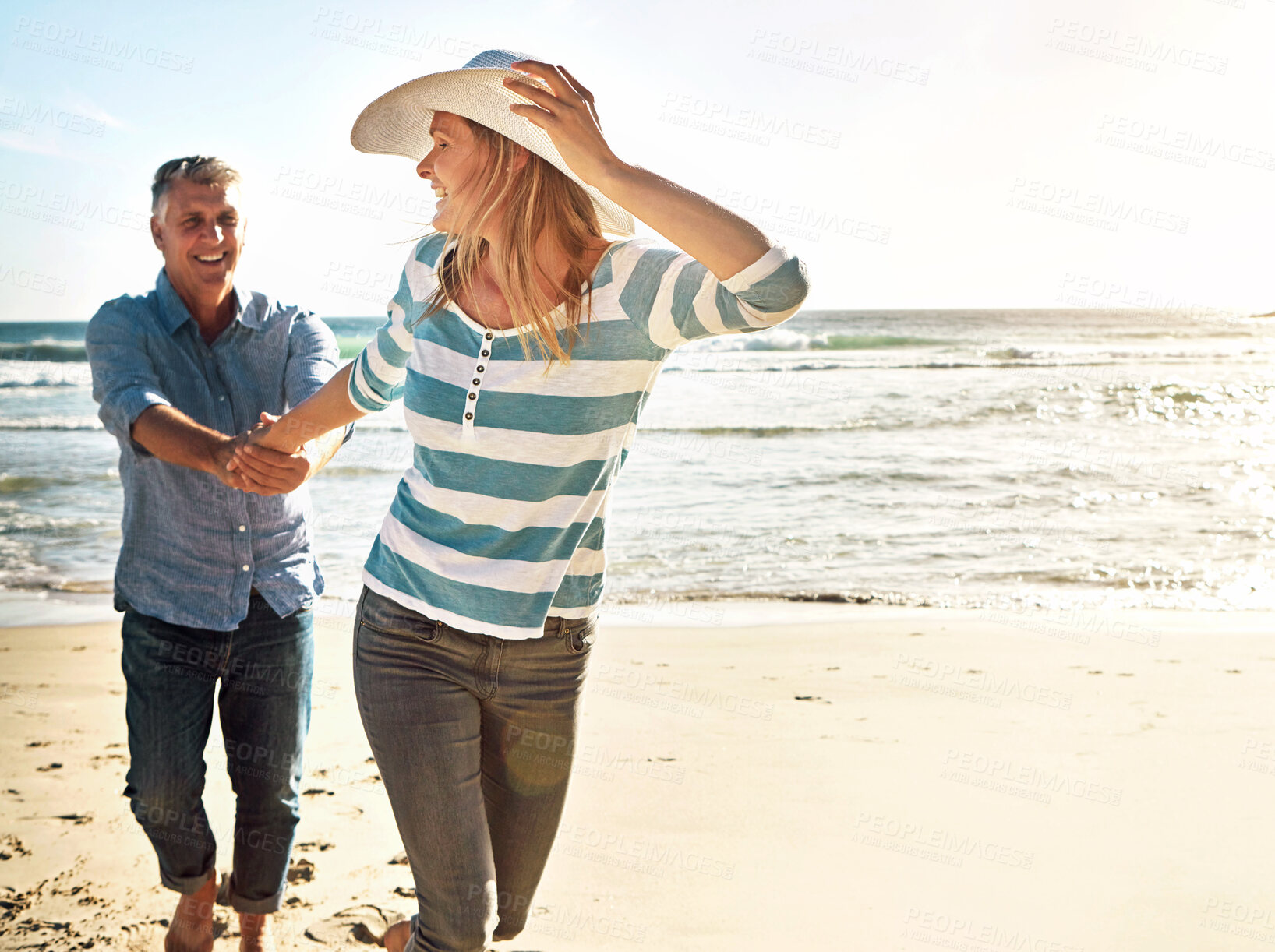 Buy stock photo Mature couple, holding hands and walking at sea on vacation, travel or summer holiday for love in nature. Happy man, woman and beach for adventure, funny or laughing on date together outdoor at ocean