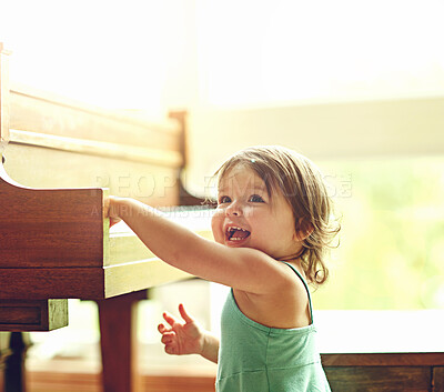 Buy stock photo Girl, toddler and playful on piano in house for musical development, learning and growth of motor skills or creativity. Child, instrument and happiness in home for entertainment, education and sound.