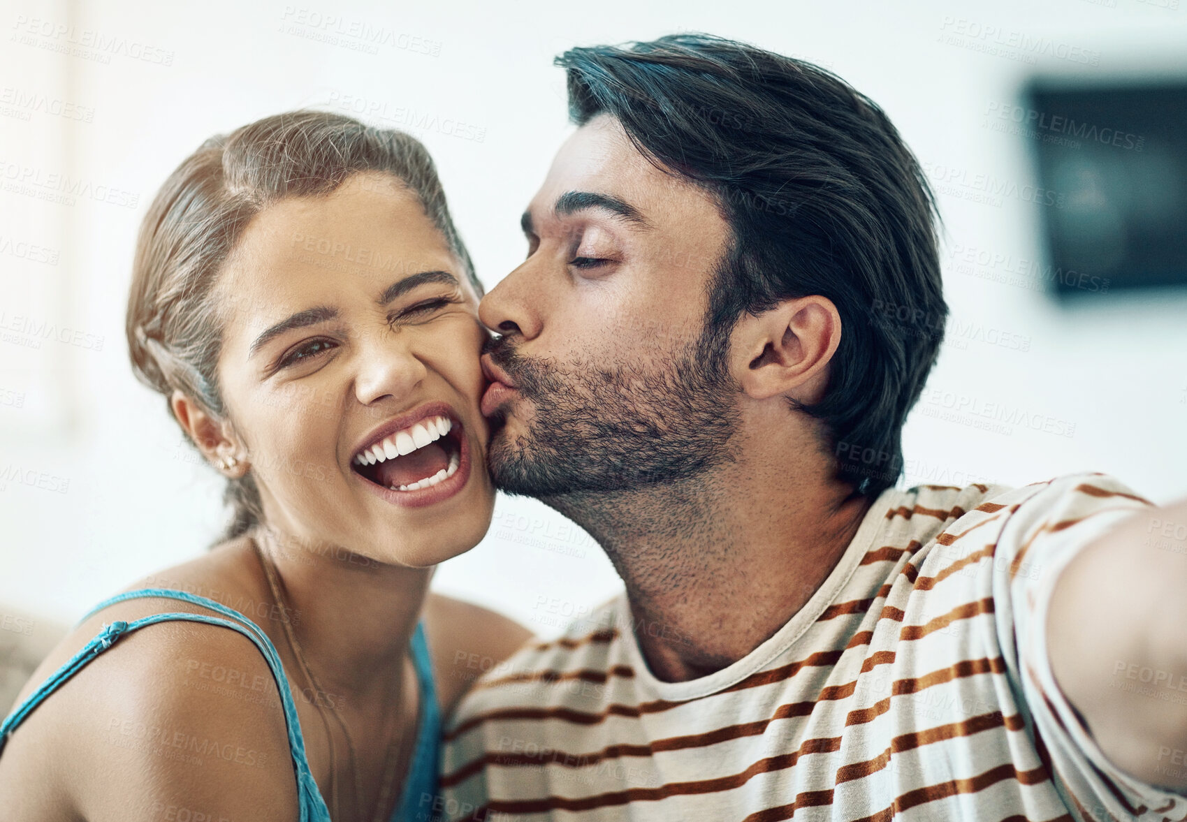 Buy stock photo Couple, selfie and kiss in home with smile, care and love for post on social media with connection. Indian man, woman and happy with photography for profile picture, excited and laughing at apartment