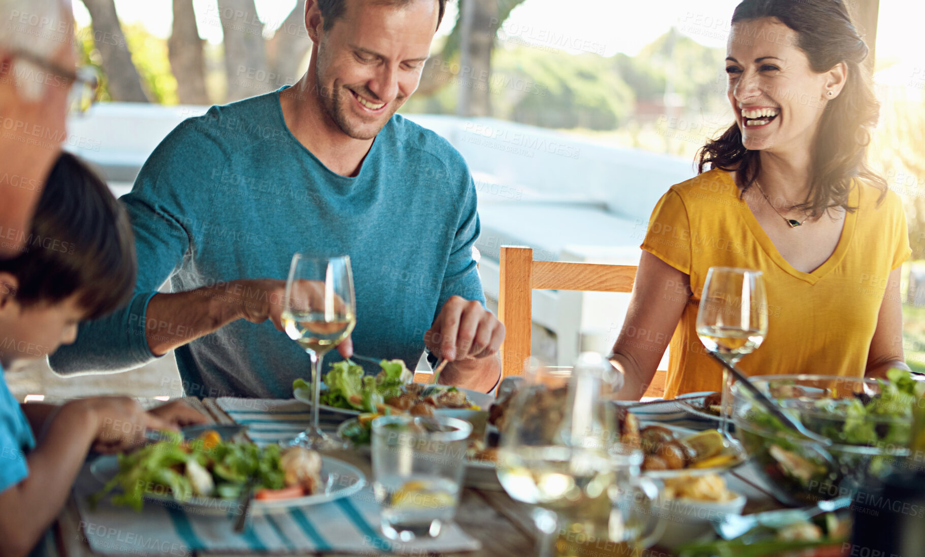 Buy stock photo Happy family, eating and lunch with laughing outdoor on patio with funny conversation, bonding and healthy food. People, dinner and relax at dining table in backyard of home with supper and talking