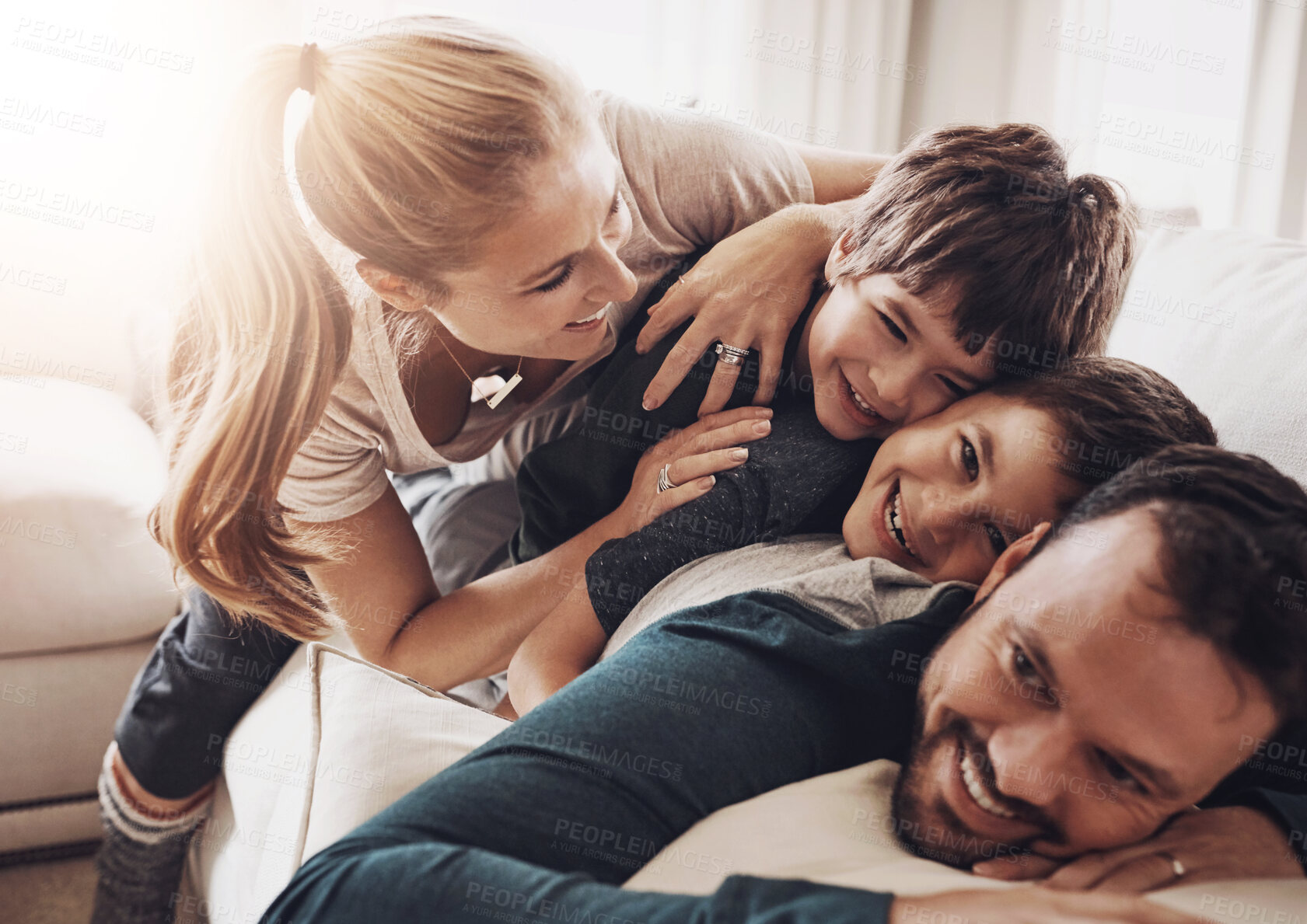 Buy stock photo Happy, parents and fun kids on a living room couch at family home playing and excited together in lounge. Hug, laughing and care on sofa with comedy, mother and morning with piggy back and youth