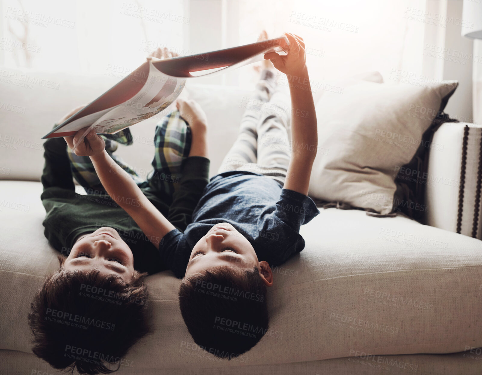 Buy stock photo Brothers, relax and reading with book on sofa for story time, leisure or literature in living room at home. Little boy, siblings or children lying on couch for novel, fairytale or chapter at house