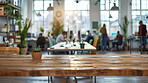 Table, wood and empty with plant or aesthetics for business, startup or workplace with light. Desk, chair and people in office for company with creative design, furniture or building with flare