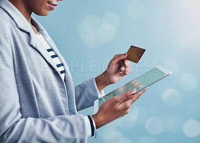 Buy stock photo Credit card for online banking, shopping and buying on tablet while standing alone isolated on blue copy space. African female paying for purchase with fintech technology on blue bokeh background