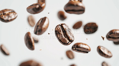 Abstract, closeup and coffee beans falling by white background for energy, latte and morning drink with caffeine. Float, studio and ingredient for premium espresso blend with strong smell and brewing