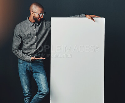 Buy stock photo Happy, black man and billboard in studio for advertising, promotion announcement and news updates on display. Male person, poster and dark background with mock up for presentation, message and sale.