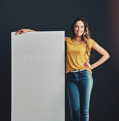 Buy stock photo Portrait, board and girl with smile, promotion and paper sign on dark studio background. Face, happy person and model with poster, mockup space and information with communication, options and opinion