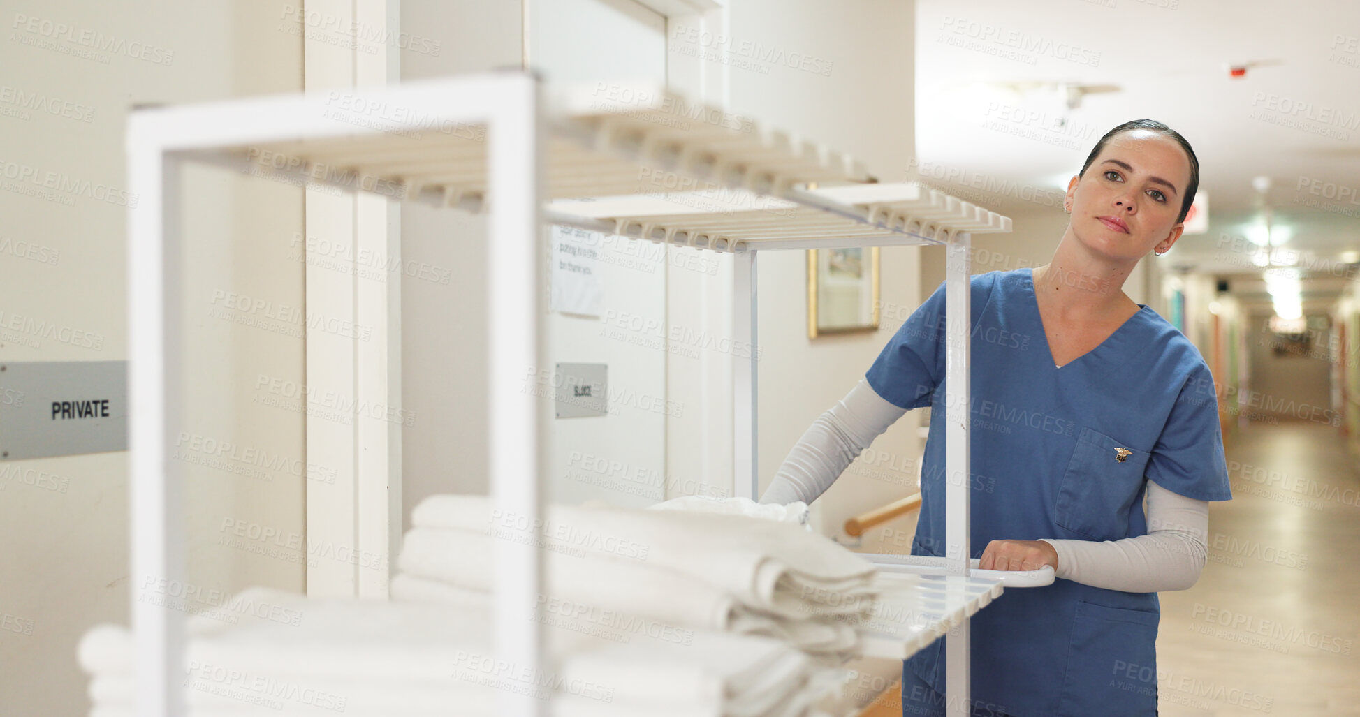 Buy stock photo Hospital, clean and towels from laundry with nurse and cart for cloth, medical and hygiene with healthcare. Nursing home, hallway and caregiver with fabric for wellness, rehabilitation and uniform