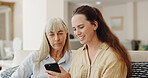 Happy, senior mom and daughter with smartphone on sofa for teaching, learning and support with care. Living room, couch and smile with browsing internet for entertainment and games at old age home