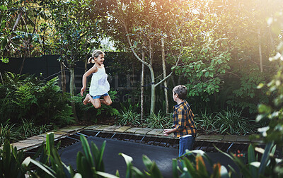 Buy stock photo Shot of an adorable little boy and girl jumping on a trampoline in the backyard at home