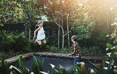 Buy stock photo Nature, jumping and children on trampoline in backyard for fun, hobby or activity together. Happy, energy and kids bounce on rebound tumbler for bonding and playing in outdoor garden with trees.