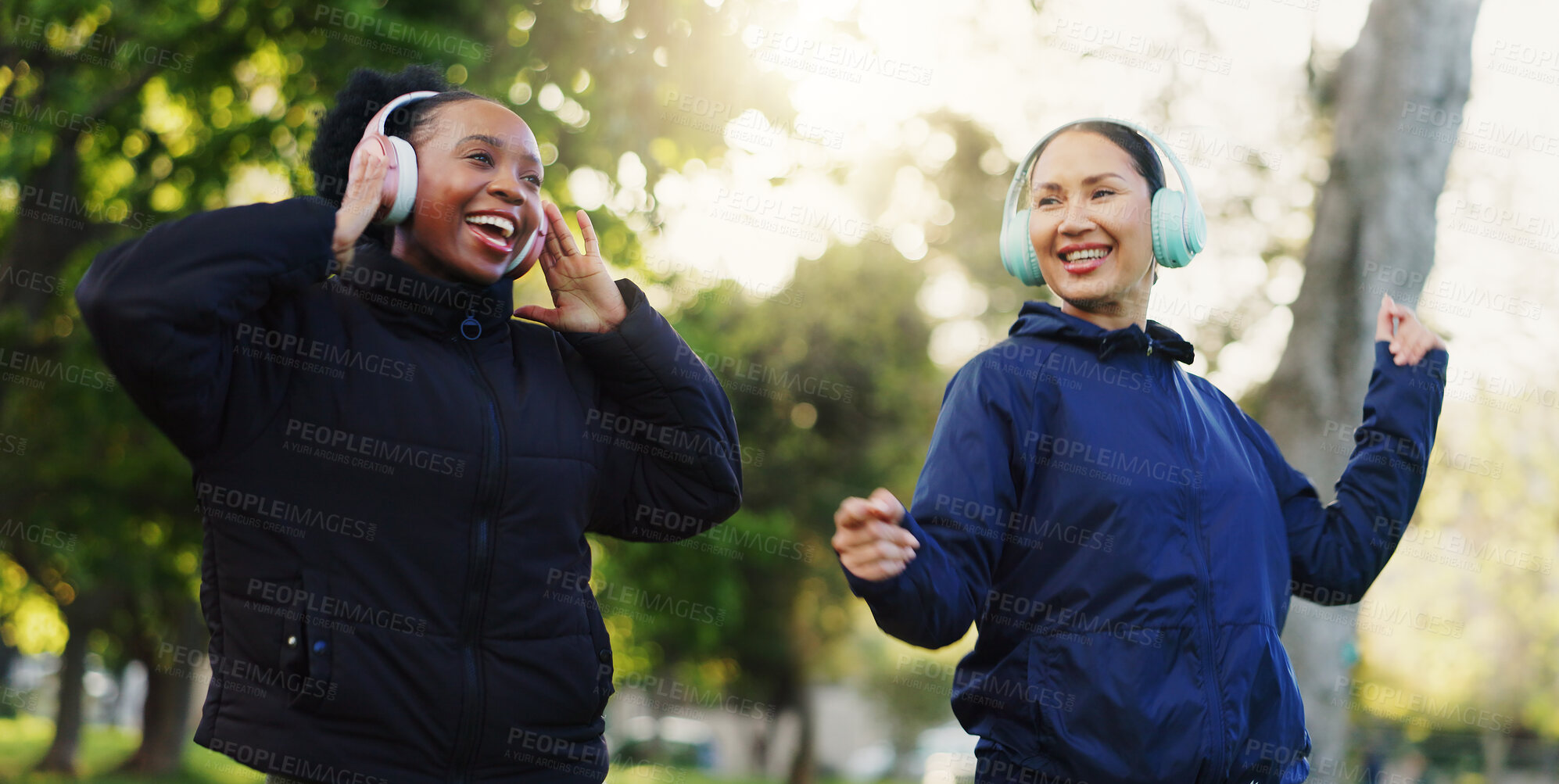 Buy stock photo Friends, women and happy in park with headphones for music or entertainment and support in Atlanta. Bonding, laugh or smile at outdoor with walk for fun, health and wellness as hobby for wellbeing