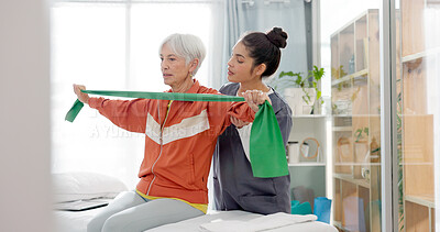 Senior woman doing a exercise with a resistance band for physiotherapy with a nurse in clinic. Fitness, healthcare and elderly female patient doing arm workout with therapist in rehabilitation center