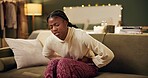 African woman, menstruation and stomach ache on sofa for pain, stress and cramps at night in living room. Girl, person and sore abdomen with virus, constipation or ibs on lounge couch in apartment