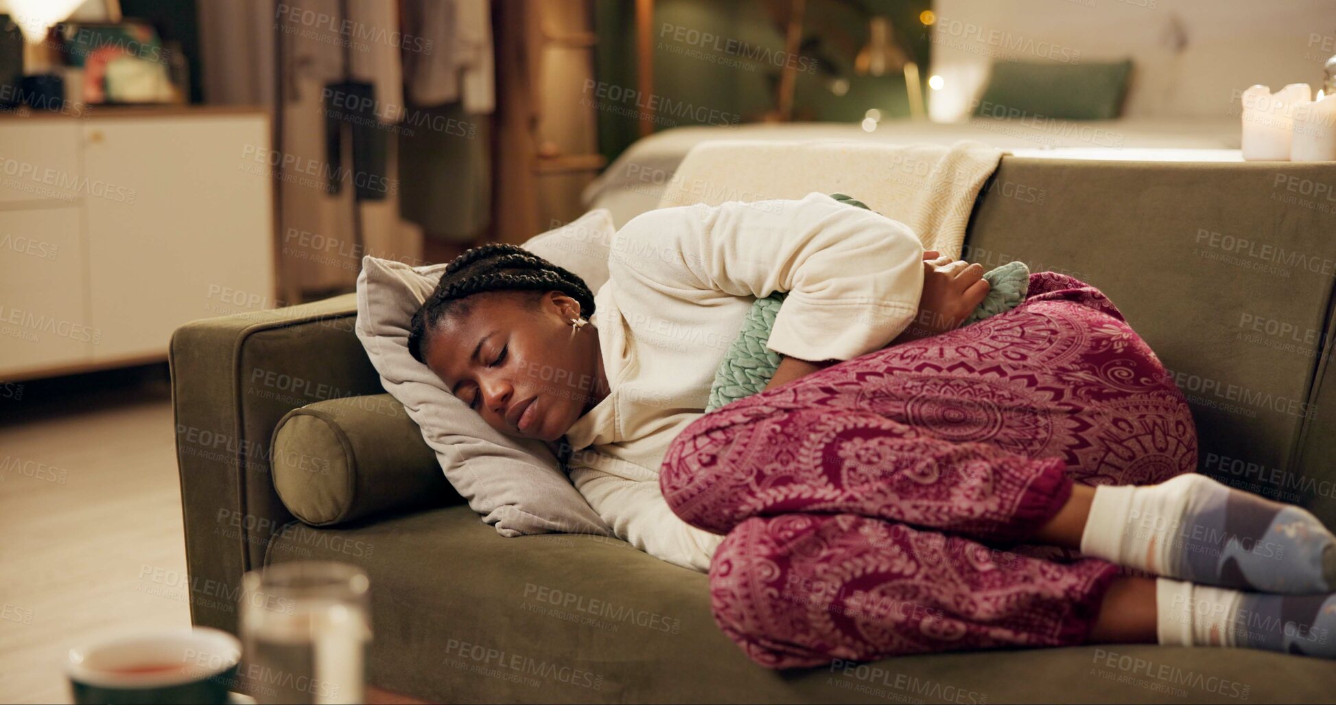 Buy stock photo African woman, menstruation and stomach on couch with pain, stress and cramps at night in living room. Girl, person and holding sore abdomen with virus, constipation and ibs on lounge sofa in home