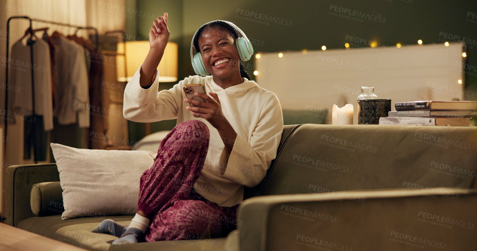 Buy stock photo African woman, headphones and phone on couch with smile, singing or dancing to music in home living room. Girl, smartphone and happy for streaming, audio subscription and mobile app on sofa in house