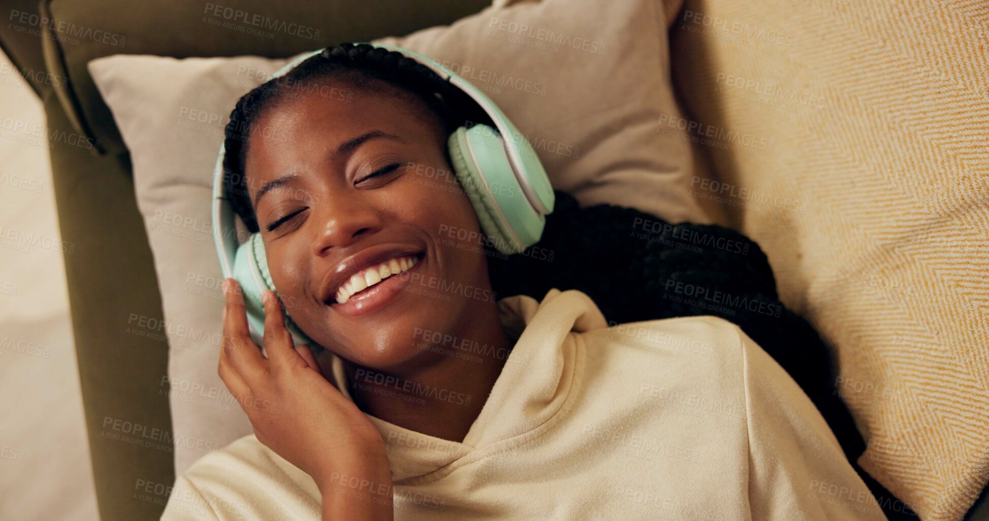 Buy stock photo African woman, headphones and above on couch with smile, relax and peace with music in home living room. Girl, listening and happy for streaming, audio subscription and lying on lounge sofa in house