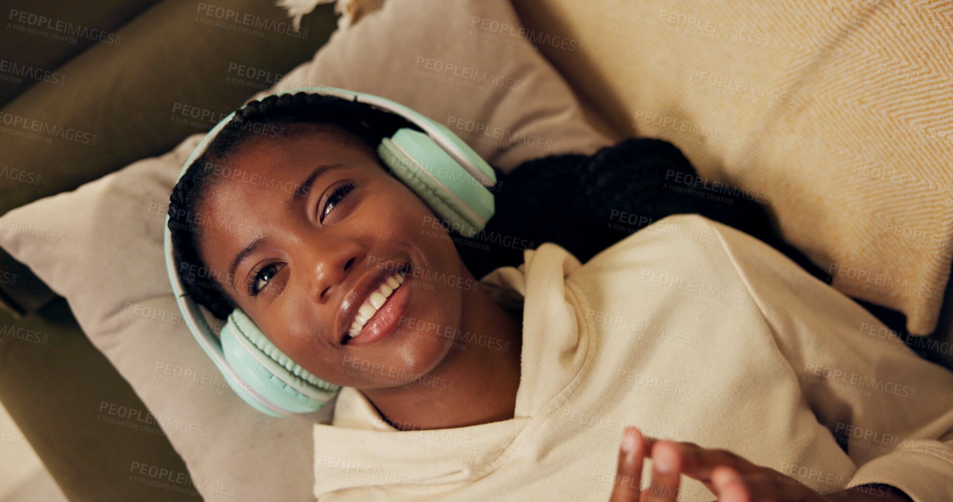 Buy stock photo African woman, headphones and above on sofa with smile, relax and singing with music in home living room. Girl, listening and happy for streaming, audio subscription or lying on lounge couch in house