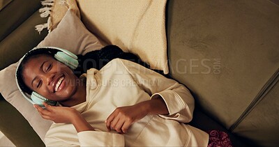 Buy stock photo African woman, headphones and lying on sofa with smile, relax and singing with music in home living room. Girl, listening and happy for streaming, audio subscription or above on lounge couch in house