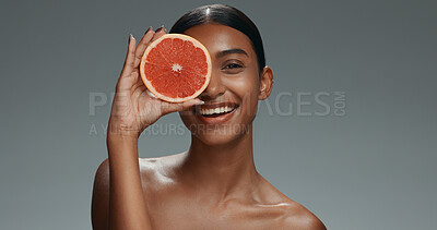 Woman, face and skincare with grapefruit, studio or shine with health, wellness or beauty by dark background. Girl, model and cosmetics with fruit, nutrition or glow with facial aesthetic in portrait