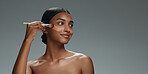 Beauty, makeup and foundation brush of a woman with cosmetics, smile and dermatology. Portrait of a happy Indian model person with facial care, skin glow and wellness on a grey background in studio