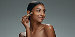 Beauty, makeup and foundation brush of a woman with cosmetics, smile and dermatology. Portrait of a happy Indian model person with facial care, skin glow and wellness on a grey background in studio