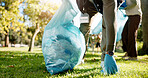 Hand, person and charity with pick up dirt at park with plastic for cleaning, care and community service. Grass, littering and waste or pollution for maintenance, environment and health as volunteer