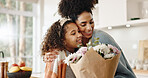 Kitchen, mother and girl with hug, flowers and present for birthday, love and family in house. Home, mom and daughter with embrace, happiness and cute in apartment, woman and child with smile