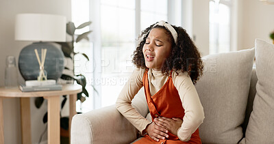 Buy stock photo Young girl, stomach ache or allergies on couch in home for health problem or digestion recovery on weekend. Child, pain or food poisoning in living room with cramps for belly discomfort and suffering