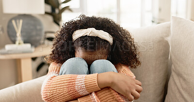 Sad girl, crying and sofa with stress in anxiety, loneliness or abuse in living room at home. Little female person, lonely child or kid alone on lounge couch with emotion, fear or grief in depression